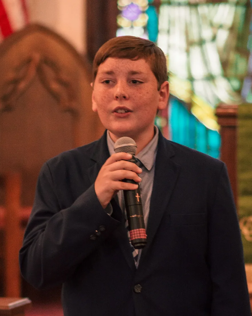 Charles Watson Jr. singing into a microphone at church