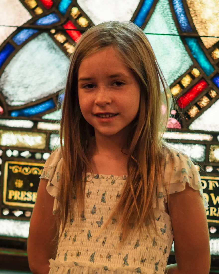 Elizabeth Watson in a white dress in front of the stained glass window